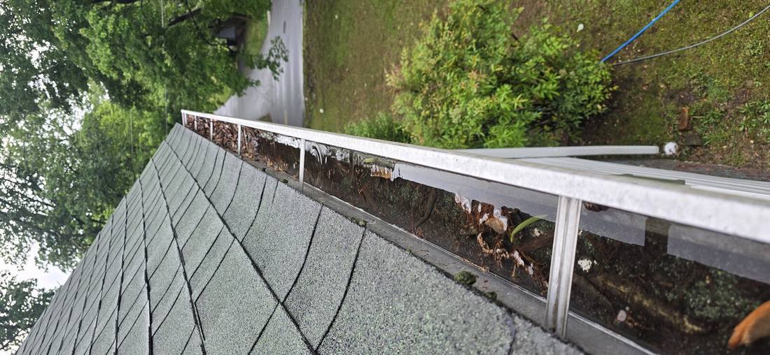 Dirty gutters with black oxidation streaks before cleaning